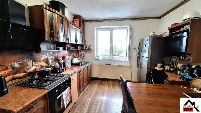 Küche eines Einfamilienhauses mit Küchenzeile, Geräten und Bodenbelag in Holzoptik.