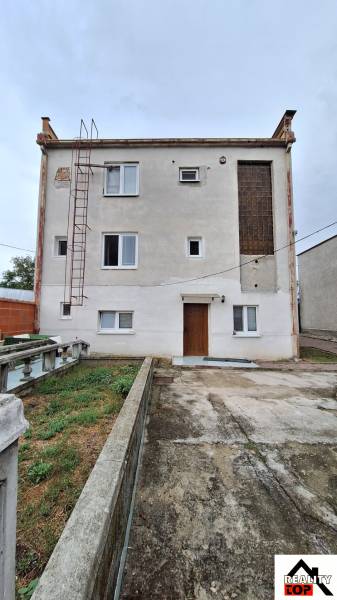 Ein Einfamilienhaus in Zacharovce mit einer einfachen Fassade, Fenstern und einer Außentreppe.