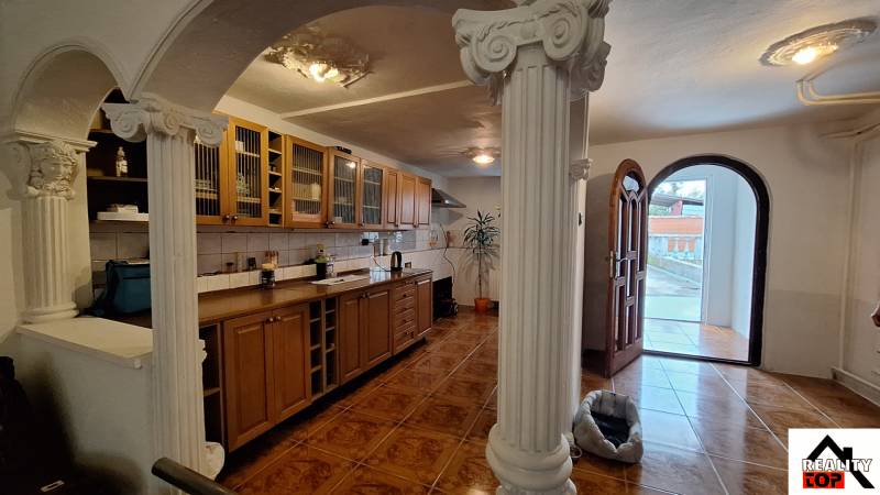 Innenraum eines Einfamilienhauses mit Holzküchenzeile, Säulen und Boden mit Holzdekor.