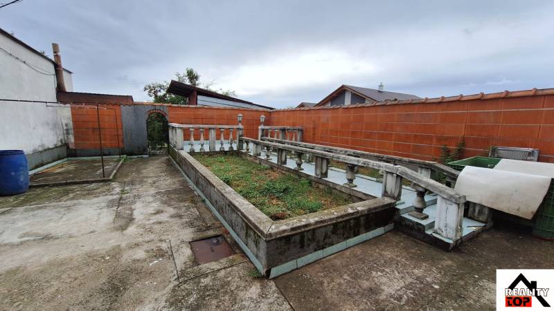 Der Hof des Einfamilienhauses in Zacharovce mit einem Blumenbeet und einem Betonweg.