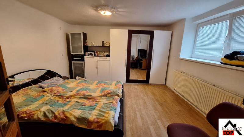 Schlafzimmer mit Bett, Schrank und Holzboden in einem Einfamilienhaus.