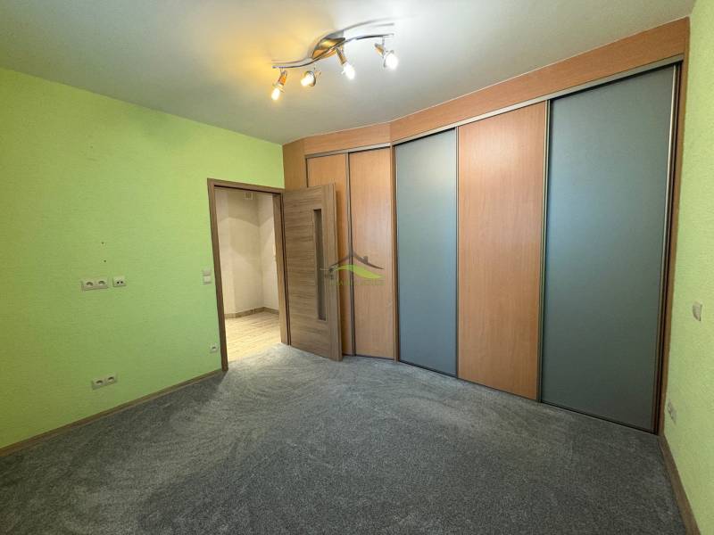 Ein Zimmer in einer 3-Zimmer-Wohnung mit einer farbigen Wand, einem Schrank und heller Beleuchtung.