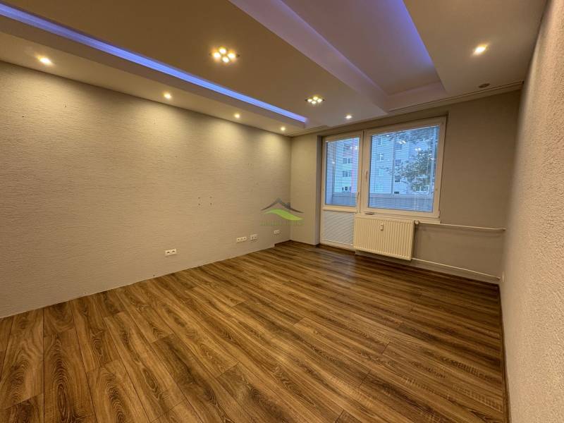 Ein Zimmer in einer 3-Zimmer-Wohnung mit Holzboden und Spotbeleuchtung.