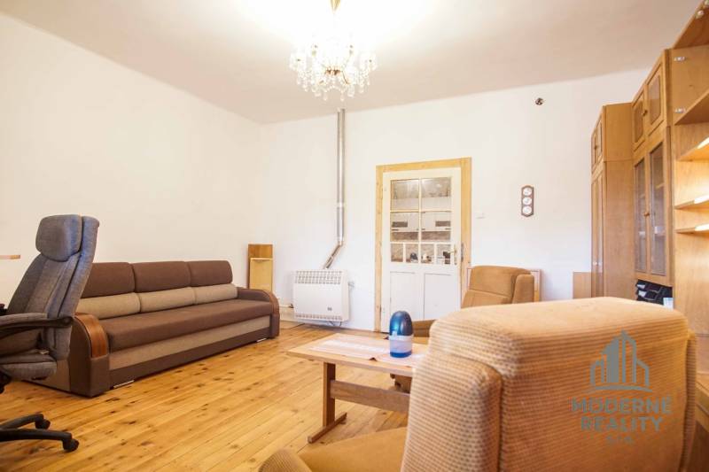 Wohnzimmer in einem Einfamilienhaus mit Holzboden, Sofa und Sesseln.