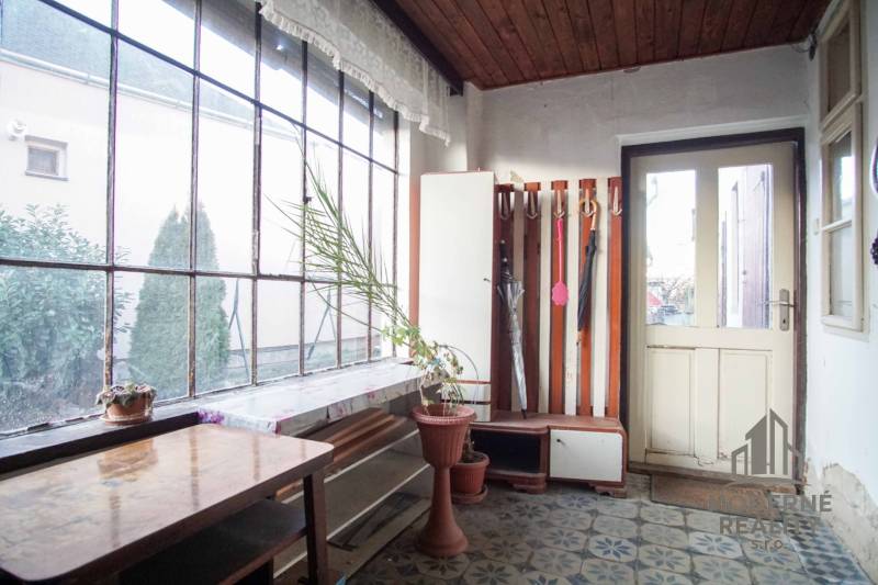 Ein Interieur in einem Einfamilienhaus mit einem Blumentopf, einem Tisch und einem Regenschirmständer.