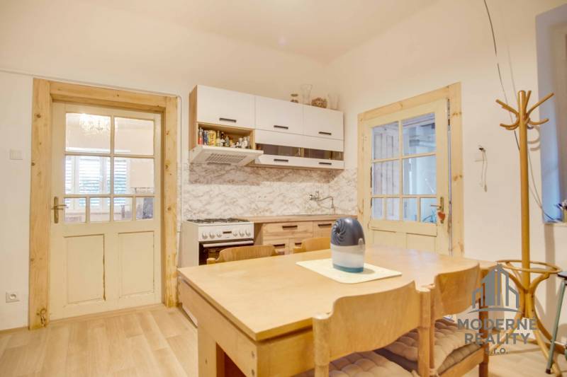 Eine Küche in einem Einfamilienhaus mit Holzmöbeln und einem Boden in Holzoptik.