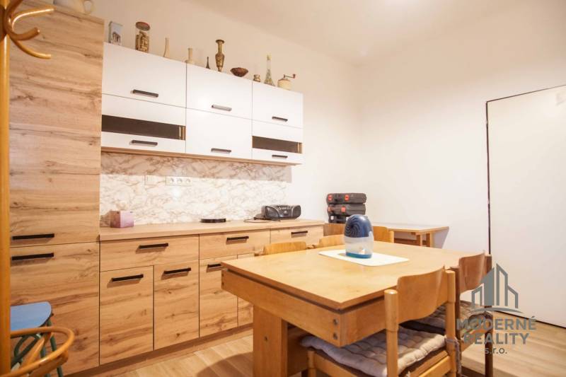 Eine Küche in einem Einfamilienhaus mit Holzmöbeln und einem Boden mit Holzdekor.