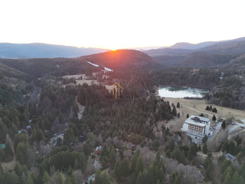 Sonnenuntergang in Krpáčovo über den Wäldern, dem See und den Gebäuden in der Straße Krpáčovo.