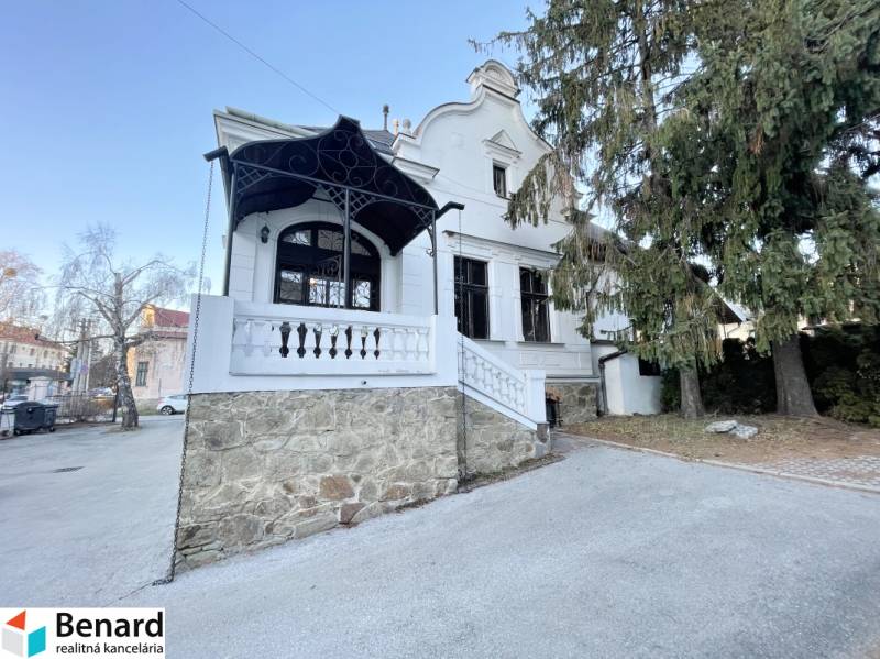 Das Gebäude in der Vajanského-Straße in Prešov mit einer Steinterrasse und Bäumen.