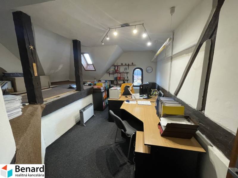 Ein Büro in einem Gebäude mit Holzbalken, ausgestattet mit Tischen und Büromaterialien.