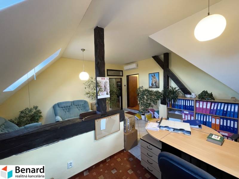 Ein Büro in einem Gebäude mit einem Holzboden, Regalen für Dokumente und einer Sitzecke.