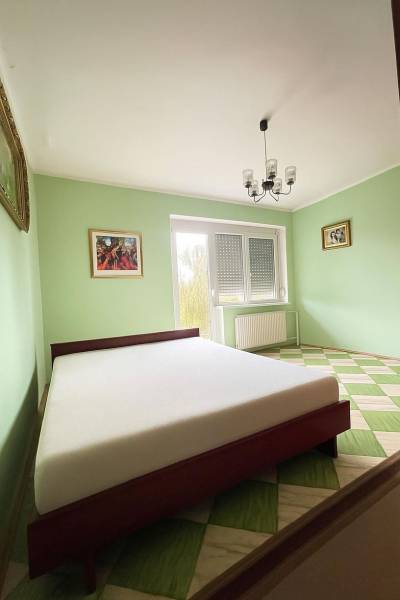 Ein Schlafzimmer in einem Einfamilienhaus mit einem Bett, pastellfarbenen Wänden und einem Schachbrettboden.