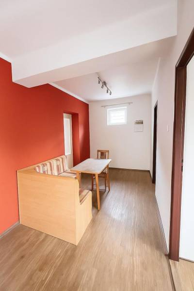 Esszimmer in einem Einfamilienhaus mit roter Wand und Boden in Holzoptik.
