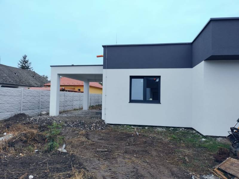 Ein Einfamilienhaus in Žihárec mit einer modernen Fassade und einer angrenzenden Pergola im Hof.