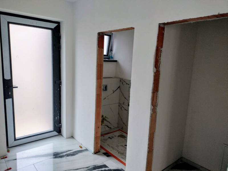 Innenraum eines Einfamilienhauses mit weißen Wänden und einem Boden mit Marmoroptik.