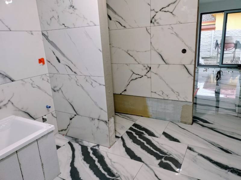 Ein Badezimmer in einem Einfamilienhaus mit Wänden und Fliesen aus Marmor.