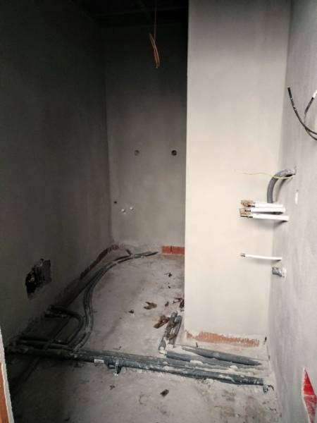 Innenraum eines Einfamilienhauses während der Renovierung mit sichtbaren Leitungen und unvollendeten Wänden.