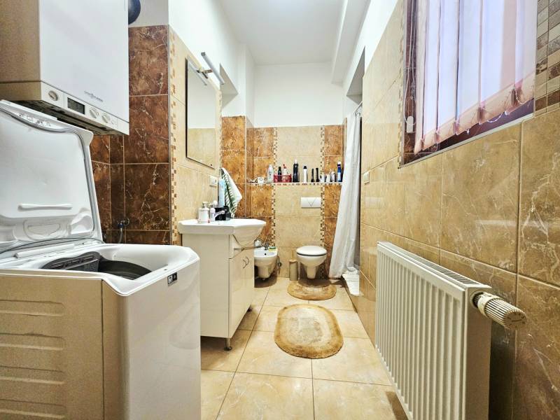 Badezimmer mit Waschmaschine, Waschbecken, Toilette und hellem Keramikfliesenboden in einer 3-Zimmer-Wohnung.