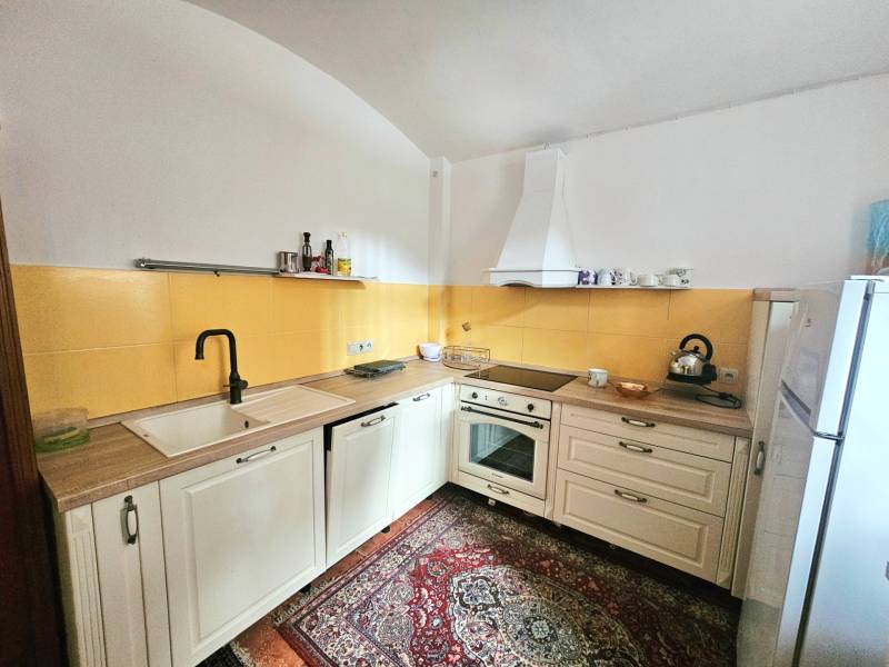 Küche in einer 3-Zimmer-Wohnung mit cremefarbenen Schränken, gelben Fliesen und gemustertem Teppich.