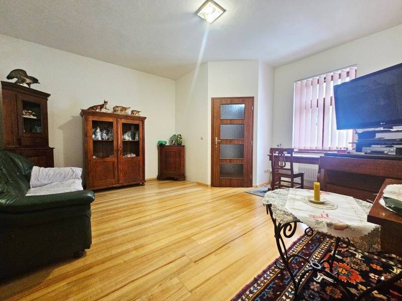 Wohnzimmer in einer 3-Zimmer-Wohnung mit Holzboden und Möbeln aus dunklem Holz.