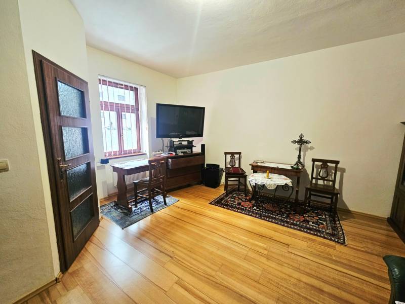 Ein Zimmer in einer 3-Zimmer-Wohnung mit einem Boden in Holzoptik und einem Fernseher auf einem Tisch.