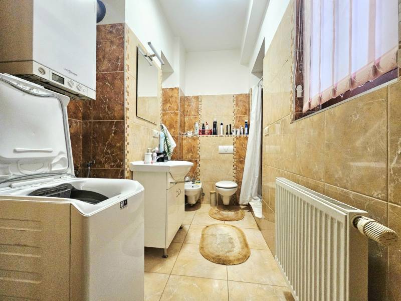 3-Zimmer-Wohnung mit Badezimmer, Waschmaschine, Badewanne und Fenster, dekorative Wandverkleidungen.