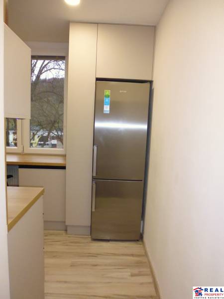 Küche mit Holzboden und Kühlschrank in einer 2-Zimmer-Wohnung.