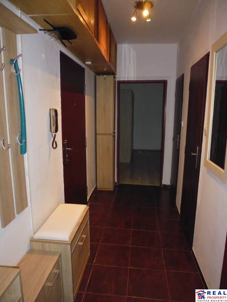 Der Flur einer 2-Zimmer-Wohnung mit dunklen Fliesen und Holzmöbeldekor.