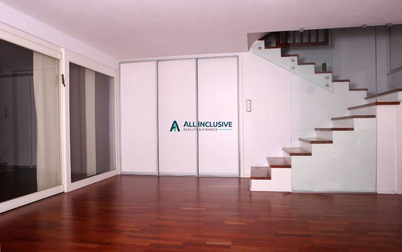 Innenraum eines Einfamilienhauses mit Holzboden und Treppe mit Glasgeländer.