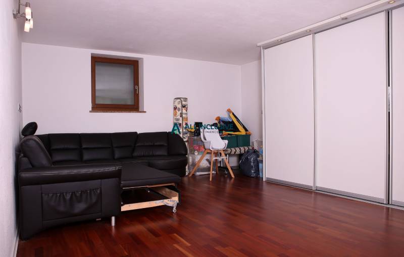 Ein Einfamilienhaus mit einem schwarzen Sofa, weißen Schränken und einem Boden mit Holzdekor.