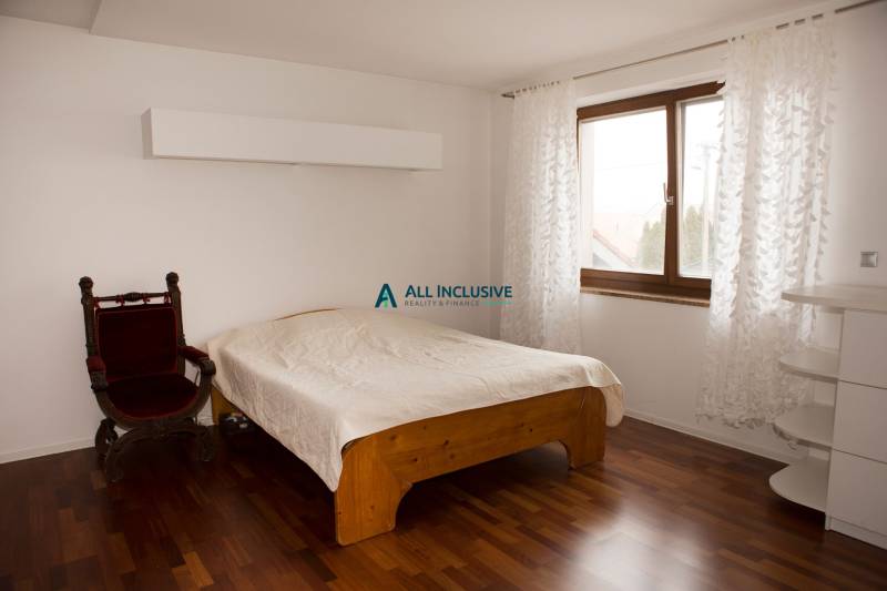 Schlafzimmer in einem Einfamilienhaus mit Bett, Sessel und Boden in Holzoptik.