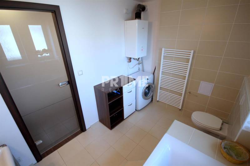 Badezimmer mit Badewanne, Waschbecken, Waschmaschine und Schränken in einer 2-Zimmer-Wohnung.