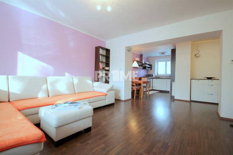 Wohnzimmer in einer 2-Zimmer-Wohnung mit einer Eckcouch und einem Boden in Holzoptik.