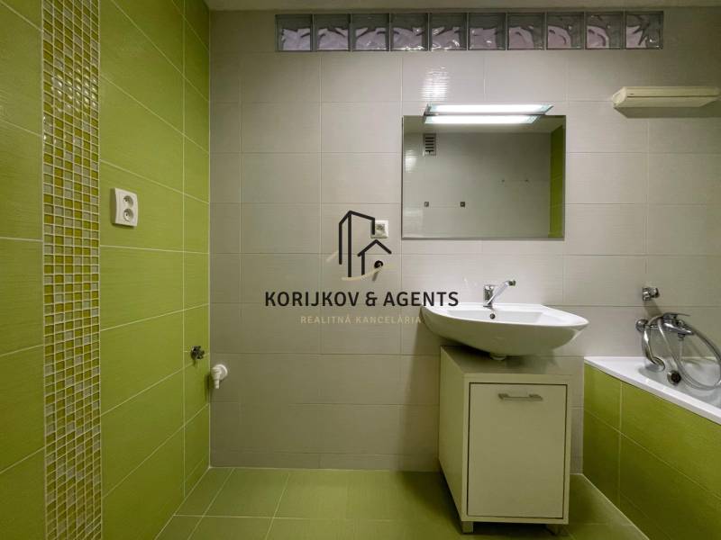 Badezimmer mit grünen Fliesen und weißem Waschbecken in einer 2-Zimmer-Wohnung.