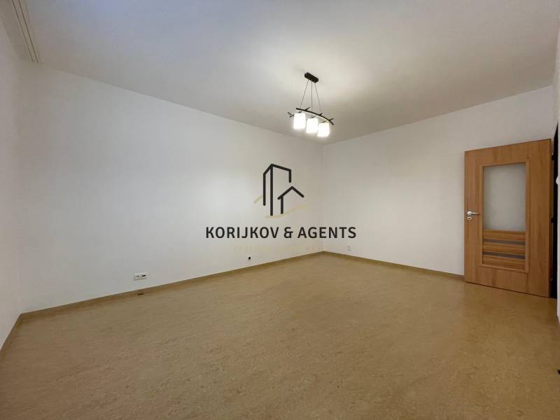 Ein geräumiges Zimmer in einer 2-Zimmer-Wohnung mit einem Boden in Holzoptik und weißen Wänden.