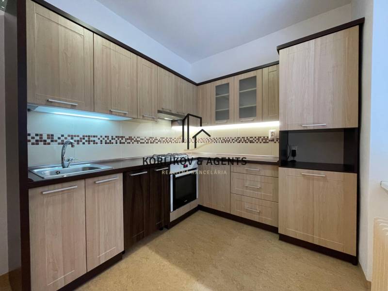 Küche in einer 2-Zimmer-Wohnung mit Holzboden und hellen Möbeln.