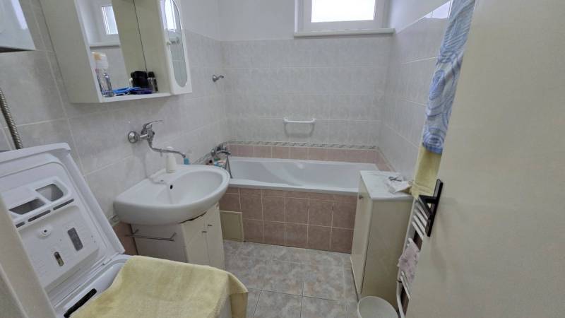 Badezimmer mit Badewanne und Waschmaschine in einer 3-Zimmer-Wohnung.