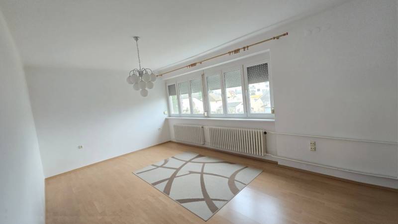 Wohnzimmer in einer 3-Zimmer-Wohnung mit Holzboden und Teppich.