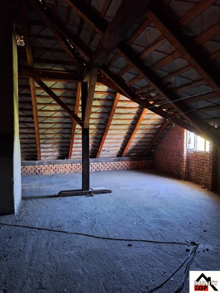 Ein Dachboden in einem Einfamilienhaus mit freiliegenden Ziegeln und der Unterkonstruktion des Daches.