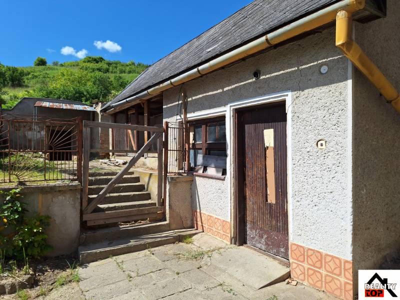 Ein Einfamilienhaus in Šíd mit einem alten Hof, einer Treppe und vernachlässigten Außendetails.