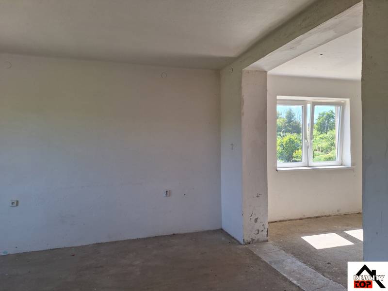 Ein unmöbliertes Zimmer in einem Einfamilienhaus mit Blick auf den Garten durch ein Kunststofffenster.