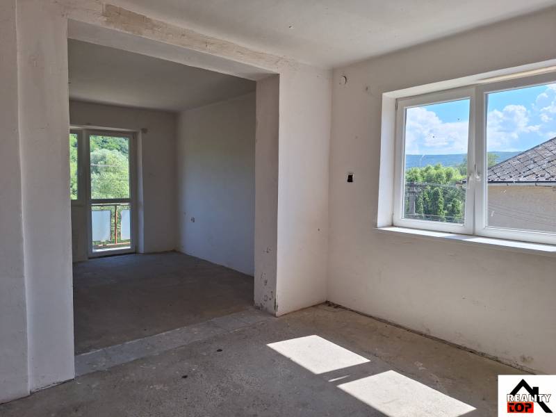 Izba v einem Einfamilienhaus, große Fenster, Blick auf den Garten und die umliegenden Bäume.