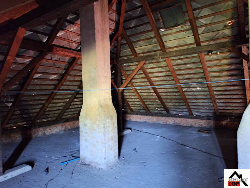 Der Dachboden des Einfamilienhauses in Šíd mit Holzbalken und Schornstein.