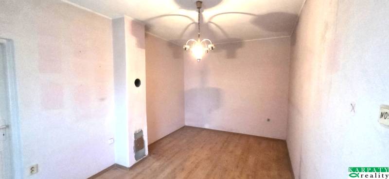 Ein Zimmer in einem Einfamilienhaus mit einem Boden in Holzoptik und einer hängenden Leuchte.