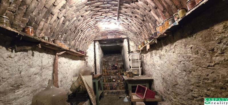 Ein traditioneller Keller in einem Einfamilienhaus, voll mit Eingemachtem und antiken Möbeln.