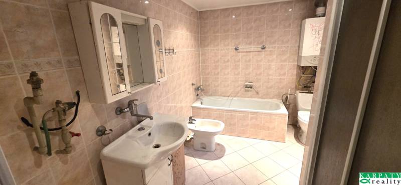 Badezimmer mit Badewanne, Waschbecken und Spiegelschrank in einem Einfamilienhaus.