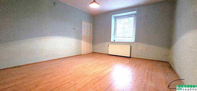 Ein Zimmer in einem Einfamilienhaus mit einem Boden in Holzoptik und blauen Wänden.