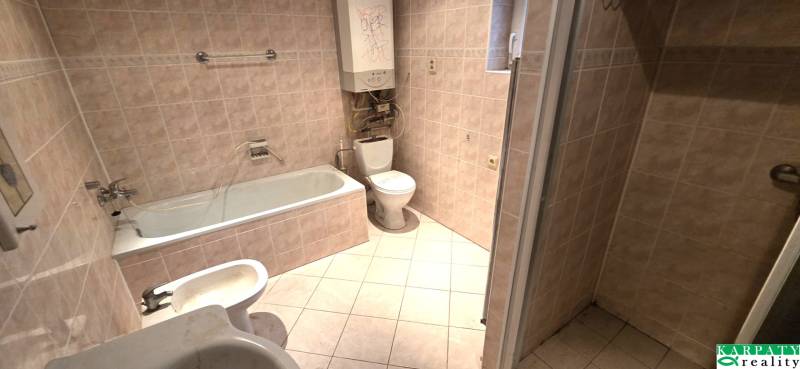 Badezimmer in einem Einfamilienhaus mit Badewanne, Waschbecken und WC. Fliesen in heller Farbe.