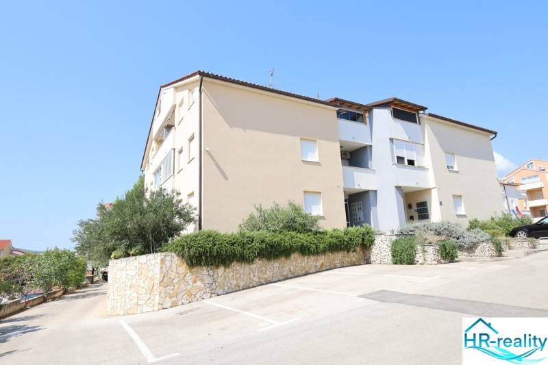 Ferienwohnung in der Stadt Vodice mit Grünflächen, Steinmauer und Parkplätzen.