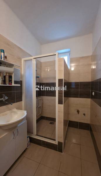 Ein Badezimmer mit Waschbecken und Dusche, in hellen Fliesentönen gehalten.